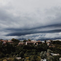 Houses on landscape against storm clouds