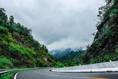 Road by trees against sky