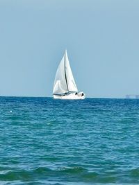 Sailboat sailing in sea against clear sky