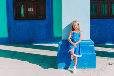 Full length of woman against blue wall