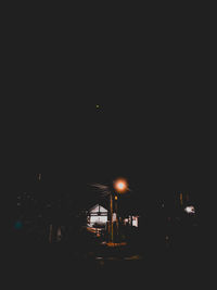 Illuminated street against clear sky at night