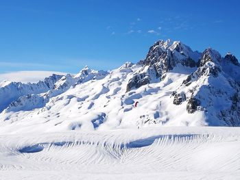 Scenic view of snowcapped mountains against blue sky