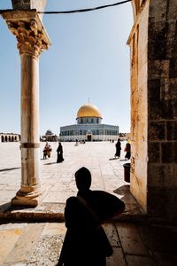 Rear view of woman standing against historic building