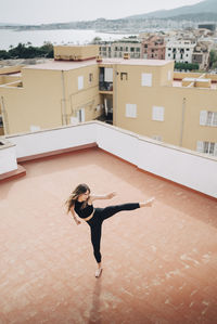 High angle view of determined woman practicing high kicks on building terrace