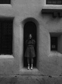 Portrait of young woman standing against building