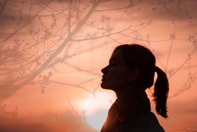 Side view portrait of young woman standing against sky during sunset