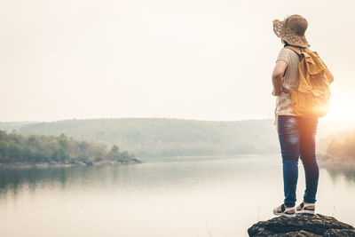 Rear view of woman standing by lake