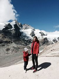 Full length of man standing on snowcapped mountain against sky