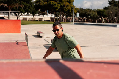 Man riding skateboard in urban street skatepark. casual guy wearing shorts and t-shirt.