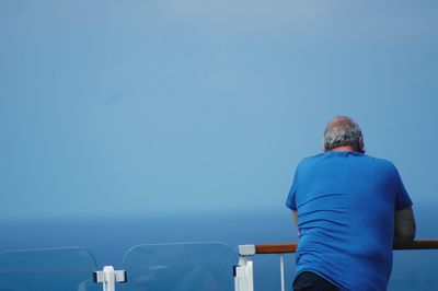 Rear view of man looking at sea against clear blue sky