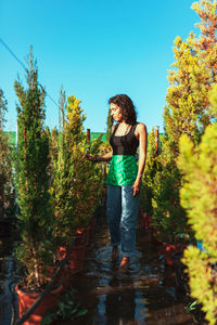 Full length of young woman standing by plants