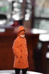 Close-up of man standing against orange wall