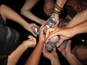 Directly below shot of people toasting drink cans