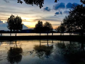 Silhouette trees by lake against sky during sunset