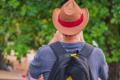 Portrait of woman wearing hat standing against trees