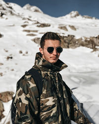 Portrait of man wearing sunglasses standing in snow