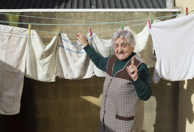 Portrait of senior woman drying clothes outdoors