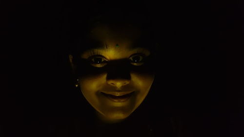 Close-up portrait of smiling mid adult man against black background