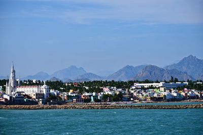 Sea by buildings in city against sky