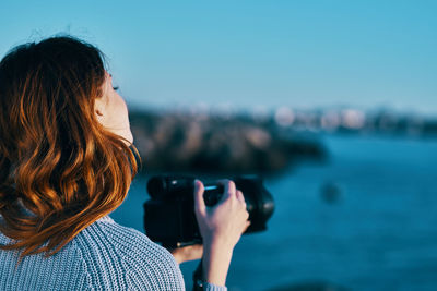 Rear view of woman photographing through camera