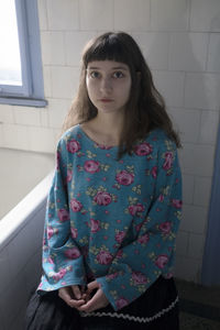 Portrait of a beautiful young woman standing against wall