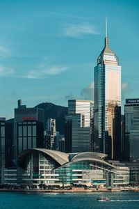 Modern buildings by river against sky in city