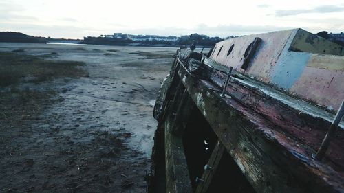 Abandoned boat moored on beach against sky