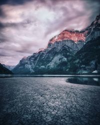 Scenic view of lake by snowcapped mountains against sky