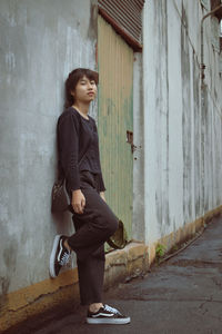 Side view of young woman standing against wall in building