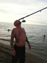 Full length of shirtless man standing on beach