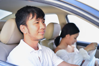 Mid adult man driving while sitting with girlfriend in car