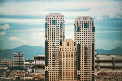 Buildings in city against cloudy sky