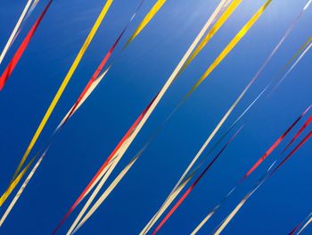 Low angle view of multi colored cables against blue sky