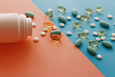 Close-up of pills spilling from bottle on yellow background