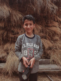 Portrait of smiling boy standing against hay