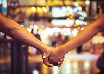 Midsection of couple holding hands at night