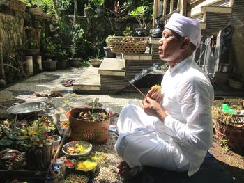 Side view of man performing spiritual activity while sitting outdoors