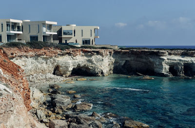 Scenic view of sea by buildings against sky