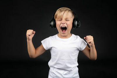 Boy standing against black background