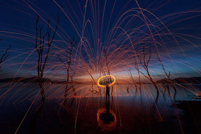 Silhouette man spinning wire wool against sky during dusk