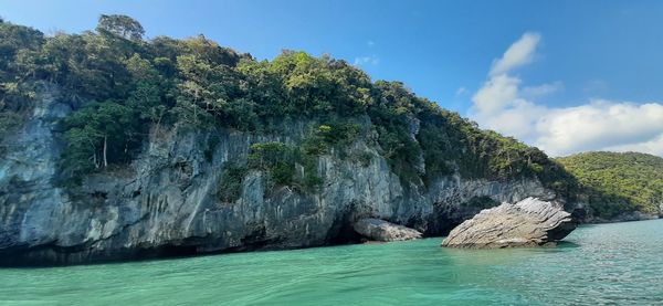 Scenic view of rocks by sea against sky