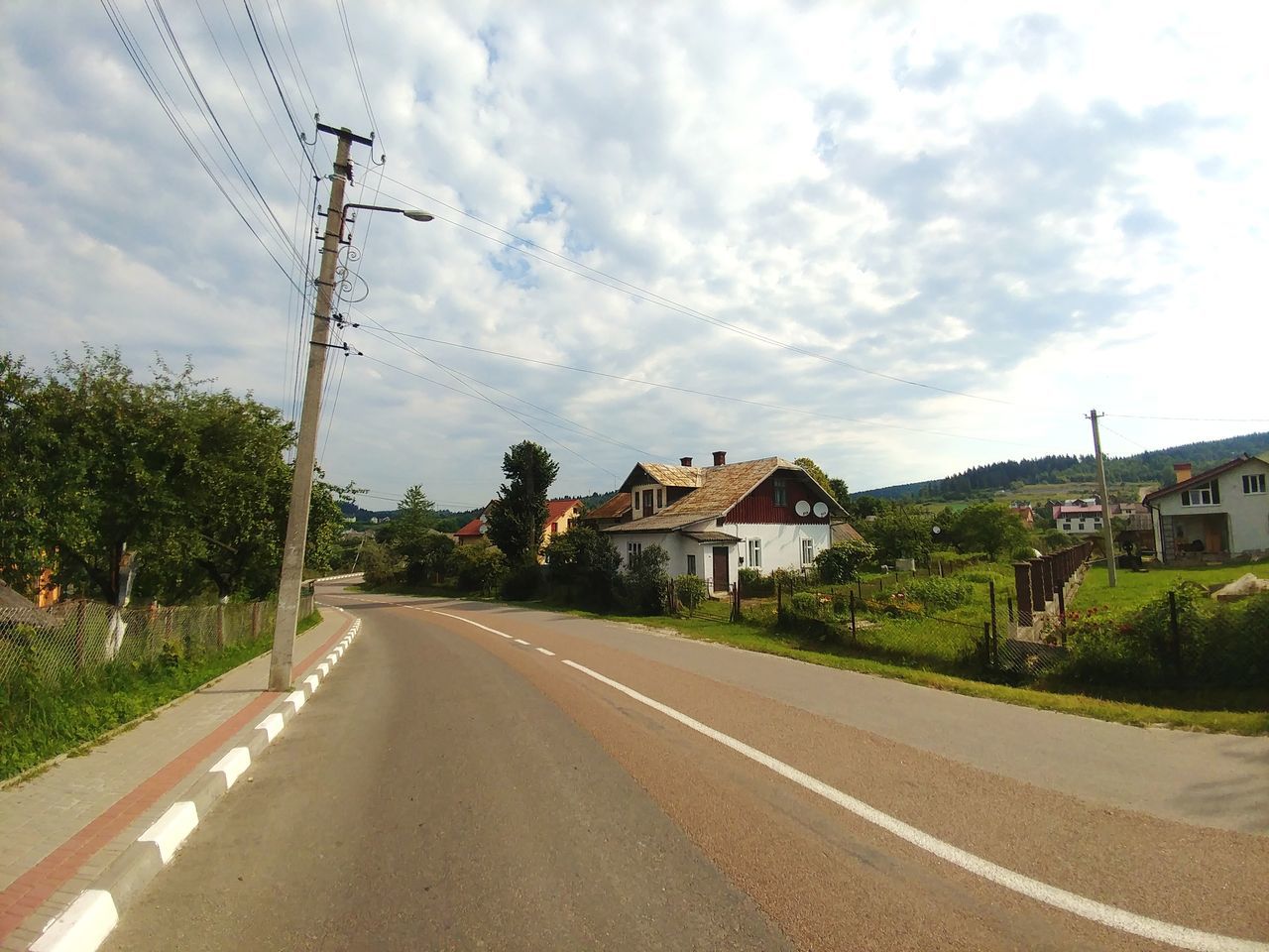 road, sky, transportation, the way forward, direction, cloud - sky, architecture, building exterior, plant, cable, electricity, nature, tree, built structure, diminishing perspective, sign, technology, power line, day, electricity pylon, no people, outdoors, telephone line, power supply