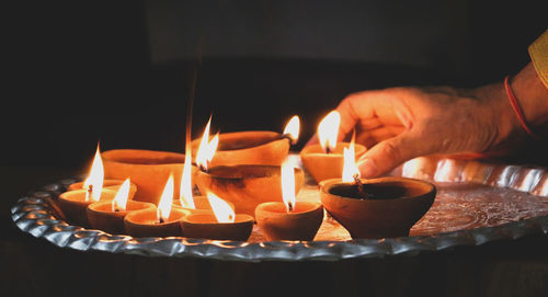 Close-up of hand holding lit diyas