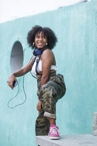 Portrait of smiling young woman standing against wall