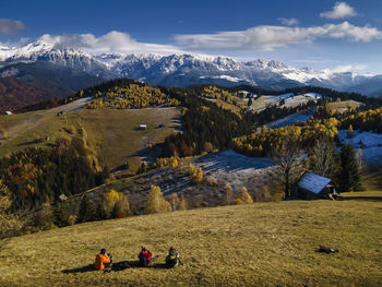 People on field by snowcapped mountains against sky