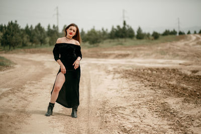 Portrait of young woman standing on dirt road