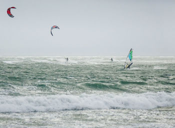 People enjoying in sea against clear sky