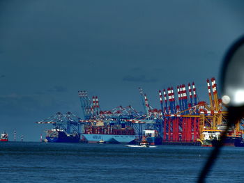 Illuminated harbor by sea against sky