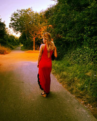 Rear view of woman standing on footpath amidst plants