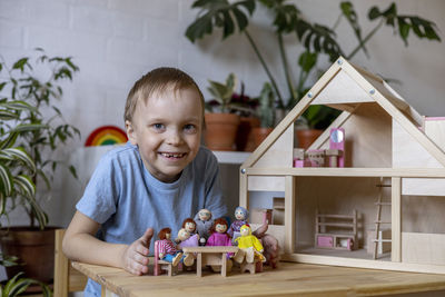 Portrait of boy sitting by house model at home